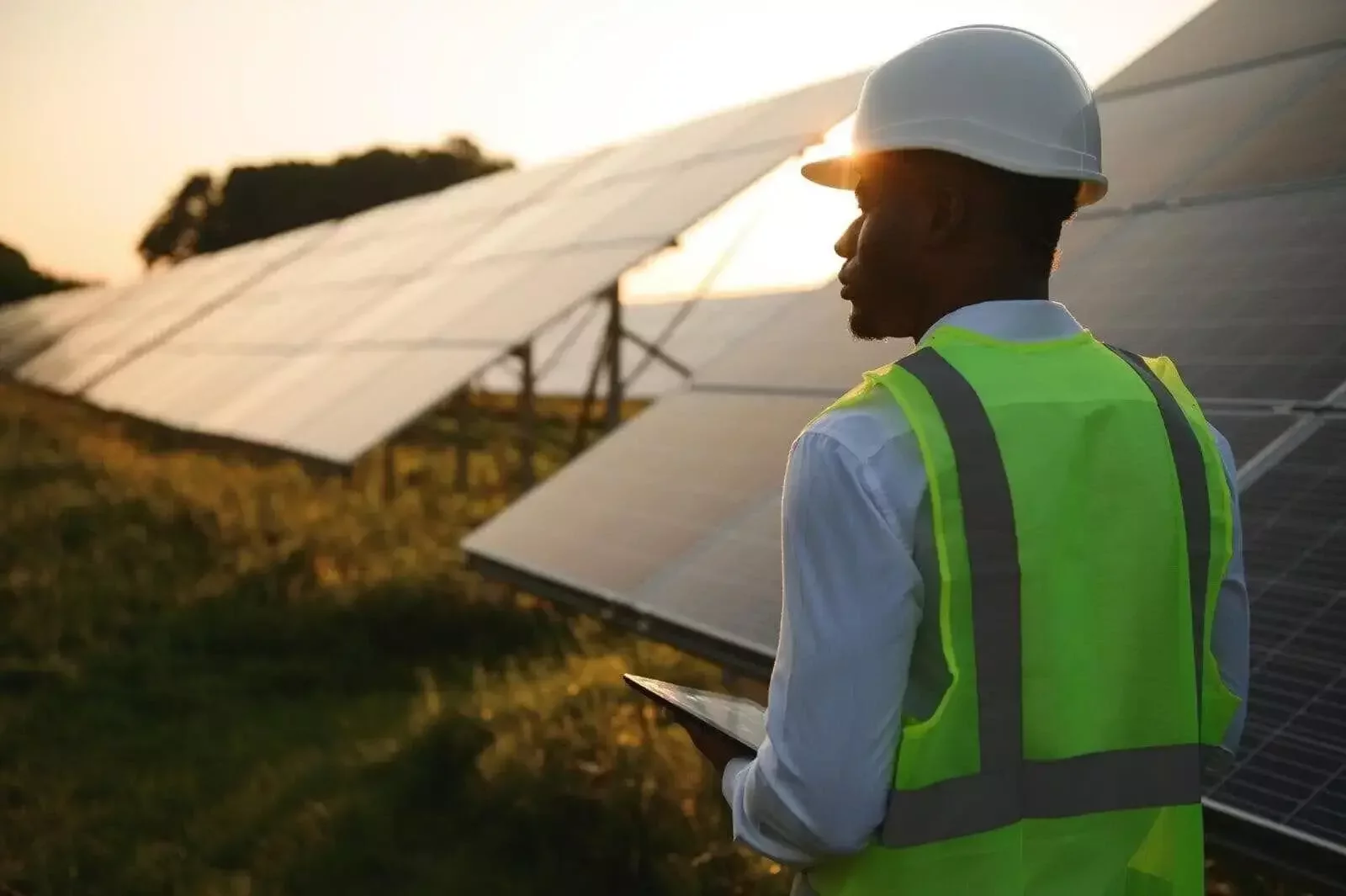Solar O&M technician with a tablet at a solar PV plant at sunset in South Africa