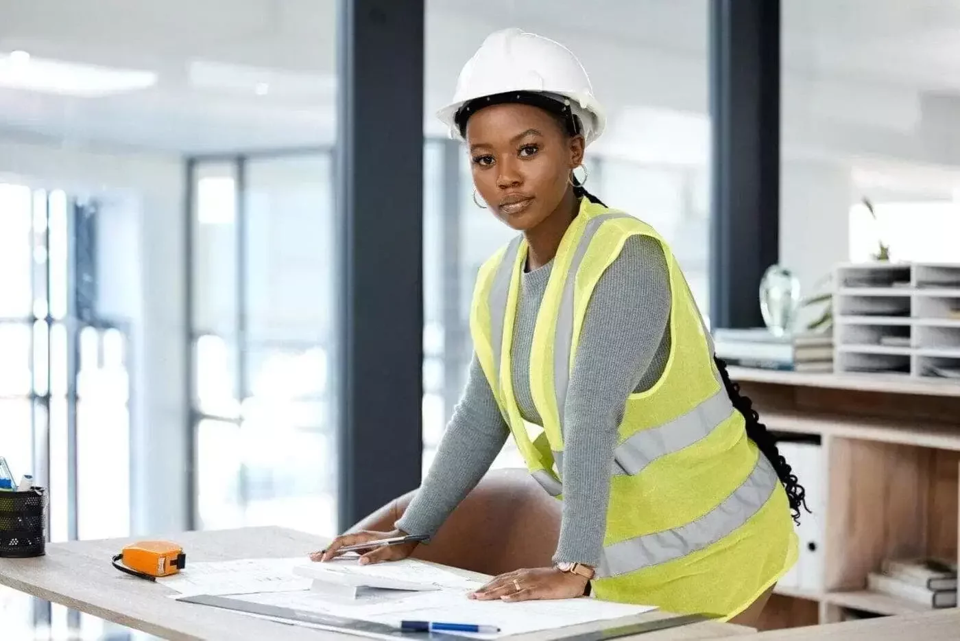 Female engineer in a hard hat and high-visibility vest reviewing technical drawings at a Solar O&M office