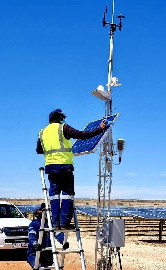 Solar O&M technician on a ladder inspecting equipment at a solar PV plant